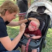 A librarians painting the face of a child in a stroller