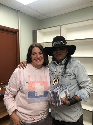 Two people smiling and holding book donations for Mexican Hat, Utah