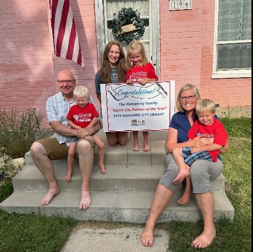 parents and four children standing around a congratulations sign